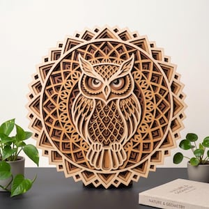 May include: A circular, multi-layered wooden wall art piece featuring a detailed owl silhouette centered within an intricate, geometric mandala pattern. The design utilizes varying shades of natural wood tones to create depth and dimension.