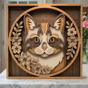 Peut inclure: Portrait de chat en bois dans un cadre carré. Le visage du chat est détaillé avec du bois clair et foncé, entouré d'un motif floral. L'œuvre est une conception en couches, créant un effet 3D. Le cadre est de couleur marron foncé.