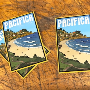 May include: Two yellow-bordered stickers with a cartoon illustration of a beach scene and the word "PACIFICA" in white letters. The stickers are on a wooden surface.