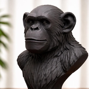 May include: A black chimpanzee bust sculpture with detailed carved features. The sculpture has a textured surface and is mounted on a tiered base. The chimpanzee's face and fur are intricately carved, showcasing the artist's skill.
