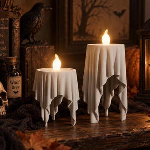 Peut inclure: Deux bougeoirs blancs en forme de tissu drapé, chacun surmonté d'une lumière LED brillante en forme de flamme. Les supports présentent une finition mate lisse et des bords irréguliers et fluides imitant l'aspect d'une nappe sur une table.