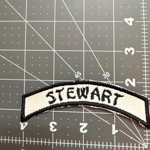 May include: A handmade wooden sign with the text "Welcome" in a handwritten style. The sign is painted white with a distressed finish, and a small, decorative heart is attached. The sign measures approximately 12 inches wide.