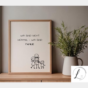 Könnte beinhalten: Ein gerahmter Druck mit dem Text "WIR SIND NICHT NORMAL - WIR SIND FAMILIE" und einer Strichmännchen-Familienillustration. Der Rahmen ist hellbraun und der Hintergrund cremefarben. Rechts steht ein weißer Krug mit Grünzeug.