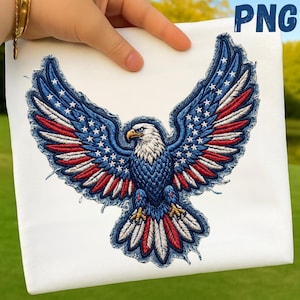 May include: White fabric with an embroidered American bald eagle design. The eagle's wings are detailed with blue, red, and white stitching, resembling the American flag. The eagle's body is blue, and the head is white with a yellow beak. The design is on a white background.