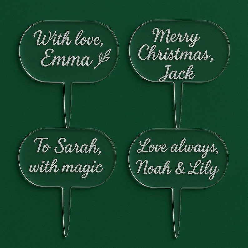 Op de afbeelding: Vier heldere acryl plantenprikkers met witte tekst. De prikkers hebben een ovale bovenkant met een puntige basis. De tekst bevat "With love, Emma", "Merry Christmas, Jack", "To Sarah, with magic" en "Love always, Noah & Lily".