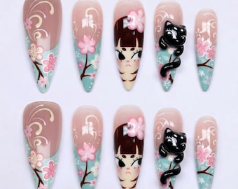 May include: Set of ten almond-shaped false nails with various designs. Some nails feature a light pink base with floral and swirl patterns. Others showcase a cartoon girl face or a black cat with a curved tail. The nails have a light blue and brown color scheme.