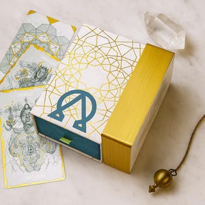 Puede incluir: Una taza de cerámica blanca con un asa negra y el texto "But First, Coffee" en negrita negra. La taza se encuentra sobre un fondo borroso, sugiriendo un ambiente acogedor.