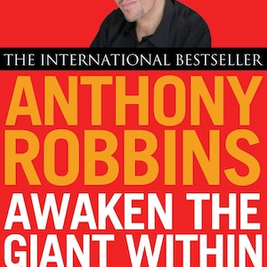 May include: Book cover with a red background and the title "AWAKEN THE GIANT WITHIN" by Anthony Robbins. The author's image is at the top. The book's title and author's name are in large, bold, orange letters.