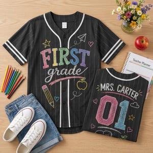 May include: A black baseball jersey with white pinstripes and white trim. The front features colorful chalk-style text reading FIRST grade, with drawings of a star, paper airplane, heart, pencil, and apple. The back displays MRS. CARTER and 01.