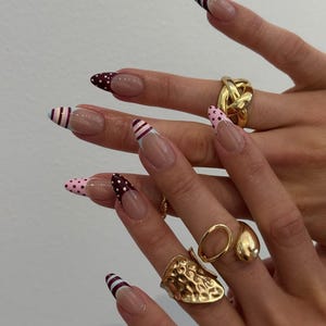 Uñas postizas con punta francesa almendrada y diseño de rayas de lunares.