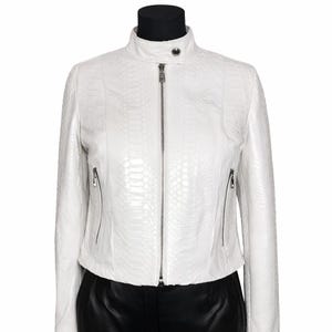 Può includere: Giacca in pelle bianca con motivo strutturato, colletto rialzato e cerniera argentata. La giacca ha due tasche con cerniera ed è esposta su un manichino nero.