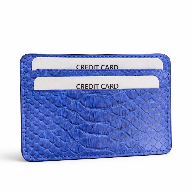 Op de afbeelding: Een blauwe creditcardhouder met een textuur, slangenleerachtig patroon. Twee witte creditcards zijn zichtbaar in de sleuven, elk met het label "CREDIT CARD". De portemonnee is rechthoekig en lijkt van leer te zijn.