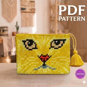 May include: A rectangular yellow crochet pouch featuring a stylised cat face design with black eyes, a red nose, and a grey mouth. The pouch includes a yellow braided cord zip pull with a matching yellow tassel attached to the right side.