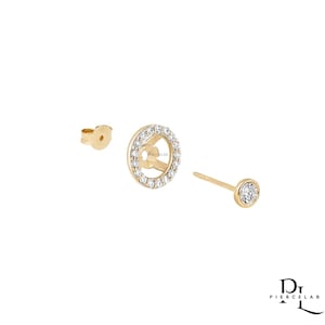 May include: Gold earrings with a sparkling design. One earring has a circular design with a halo of small, clear stones. Another earring has a single, round, clear stone. A third earring back is also visible.