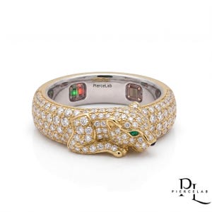 May include: A gold ring featuring a pavé-set panther motif covered in clear round stones, with green stone eyes and a black nose. The interior band is silver-toned, displaying the text PierceLab and two small electronic sensor components.