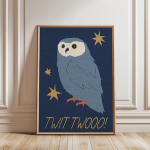 以下が含まれることがあります： 暗い青色の背景に青いフクロウのイラストが描かれた額入りのアートプリント。金色の星と「TWIT TWOOO！」の文字が金色で描かれています。アートワークは、白いパネルと木製の床がある部屋に展示されています。