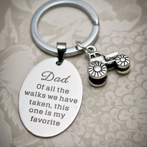 May include: Silver keychain with a tractor charm and an oval tag engraved with the text "Dad Of all the walks we have taken, this one is my favorite".