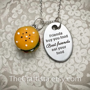 May include: Silver necklace with a small hamburger charm and a silver oval pendant with the text "Friends buy you food Best friends eat your food".