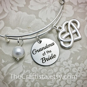 May include: Silver charm bracelet with a pearl charm, an infinity heart charm, and a round charm that says "Grandma of the Bride".