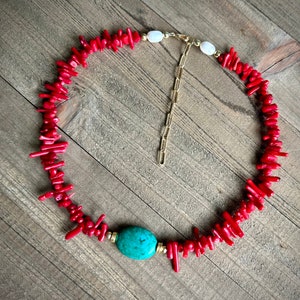 May include: A red coral necklace with a turquoise stone pendant and a gold chain clasp.