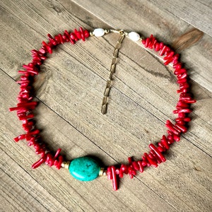 May include: A red coral necklace with a turquoise stone pendant and gold chain accents.