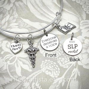 Könnte beinhalten: Silbernes Armband mit mehreren Charms, darunter ein Herz-Charm mit den Worten "Danke", ein medizinisches Symbol-Charm, ein runder Charm mit den Worten "Jeder verdient eine Stimme" und ein runder Charm mit den Worten "Dieser SLP rockt!"