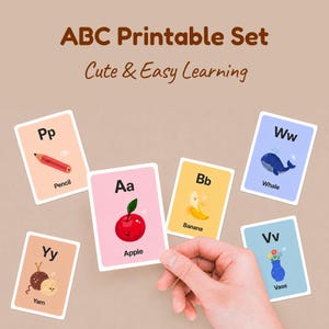 A person's hand holding a pink 'Aa for Apple' card among other scattered alphabet cards like Pencil, Whale, and Yarn. The title reads 'ABC Printable Set - Cute & Easy Learning' on a neutral background.