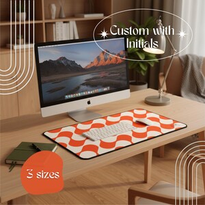 May include: A desk setup featuring a computer, keyboard, and mouse on a wooden desk. A patterned orange and white mousepad with a black border is the focal point. Text on the image reads "Custom with Initials" and "3 sizes".