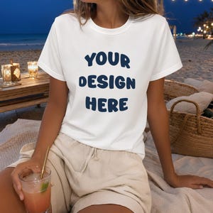 Peut inclure: Un t-shirt blanc à manches courtes avec le texte bleu foncé "YOUR DESIGN HERE" imprimé dans une police arrondie et audacieuse sur la poitrine. Le t-shirt présente un col rond classique et un ourlet droit, offrant un aspect simple et épuré.