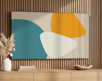 May include: A modern living room scene featuring a large abstract art piece with teal, yellow, and white shapes. Below, a light wood floating media console holds a white vase with dried flowers, books, and a wooden bowl. The wall is paneled with vertical wood slats.