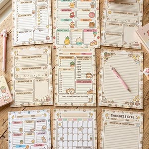 Può includere: Una collezione di planner settimanali e mensili a tema kawaii con simpatiche illustrazioni. I planner presentano sezioni per obiettivi, compiti, note e affermazioni. Sono visibili anche una penna rosa e una piccola pianta in vaso.