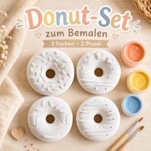 Può includere: Un kit creativo composto da quattro forme di ciambella in ceramica bianca con varie texture in rilievo, tre piccoli contenitori rotondi di vernice color pesca, giallo e azzurro, e due pennelli in legno. Il testo riporta Donut-Set zum Bemalen.