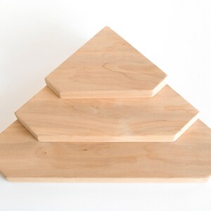 Puede incluir: Tres estantes de madera sin terminar dispuestos en forma escalonada. Los estantes son de color claro, con una veta de madera natural. El estante superior es triangular, el del medio es un hex&aacute;gono y el inferior es un hex&aacute;gono m&aacute;s grande.