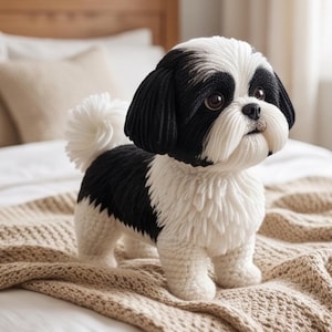 May include: A handcrafted stuffed dog toy featuring a black and white colour scheme. The plush figure has long, textured black ears, a white muzzle, and dark brown eyes. It stands on four short legs with a fluffy white tail and detailed yarn work.