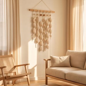 May include: A wall hanging featuring cream-colored macrame cord knotted into six vertical spiral strands suspended from a horizontal wooden dowel. Two small, round, dark brown wooden beads are threaded onto the top of the central strands.