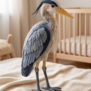 Può includere: Una statuetta di airone realizzata all'uncinetto a mano con piumaggio testurizzato nei toni del blu ardesia, grigio e crema. L'uccello presenta un lungo becco giallo, zampe grigio scuro e una cresta di fibre di lana blu scuro sulla nuca.