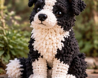 May include: A crocheted stuffed animal in the likeness of a dog with black and white yarn. The dog features a white chest, white paws, and a white stripe on its face, with dark, glossy eyes and a black nose, sitting in an upright position.