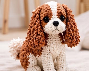 May include: A crocheted stuffed dog toy featuring a brown and white color pattern. The dog has long, textured brown ears, large black plastic eyes, a small black nose, and a white tail. The body is crafted with visible yarn stitches.