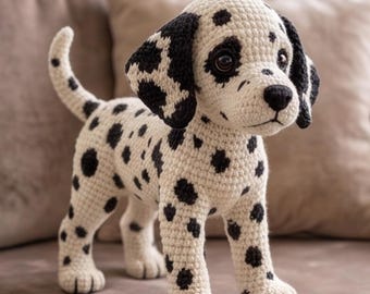 May include: A handmade crochet dalmatian puppy toy featuring an off-white yarn body with distinct black spots, dark brown plastic eyes, a black stitched nose, and floppy ears. The plush dog stands on four legs with a raised tail.