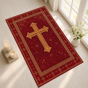 Puede incluir: Una alfombra rectangular roja con un diseño de cruz dorada. La alfombra presenta un patrón floral detallado y un borde dorado con motivos de cruz. La cruz está centrada y tiene una apariencia tridimensional.