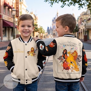 May include: A cream and black varsity jacket featuring The Lion King graphics. The front displays the movie logo and character group, while the back showcases a large illustration of Simba, Mufasa, Scar, and other characters with the text Est. 1994.