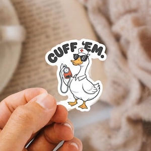 May include: A white sticker featuring a cartoon goose wearing sunglasses and a nurse's hat with a red cross. The goose holds a blood pressure monitor and the text "CUFF 'EM" is above it.