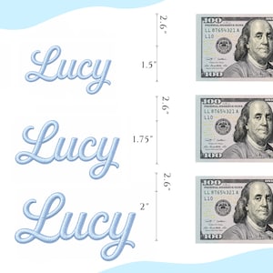 May include: Three light blue embroidered patches featuring the name Lucy in a cursive script font. Each patch is displayed next to a 100 dollar bill for scale, with vertical measurements of 1.5 inches, 1.75 inches, and 2 inches clearly indicated.
