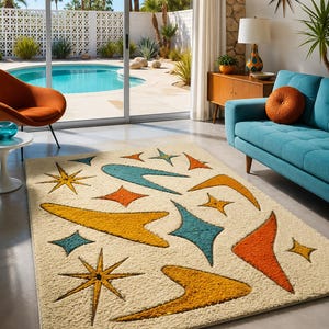 May include: A cream-coloured mid-century modern rug featuring a pattern of yellow, orange, and teal starbursts and boomerangs. The rug is in a living room with a blue sofa and a view of a swimming pool.
