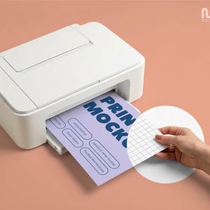 May include: A white printer is shown printing a light purple sheet of paper with the words "PRINT MOCK" in dark blue. A hand is peeling back a white, grid-patterned sticker from the printed sheet. The background is a solid peach color.
