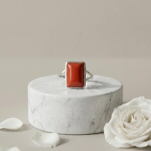 Handgemaakte ring met rode koraal in zilver, rechthoekige ring met edelsteen in een zetting, opvallende ring met gespleten band, ideaal als jubileum- of verjaardagscadeau.