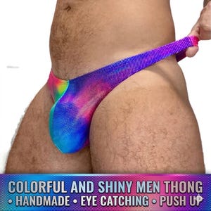May include: A colorful thong with a rainbow gradient design. The fabric has a shiny, dotted texture. The text at the bottom reads: "COLORFUL AND SHINY MEN THONG - HANDMADE - EYE CATCHING - PUSH UP."