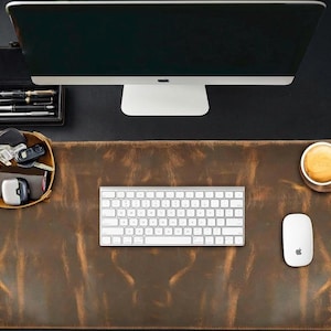 Puede incluir: Un tapete de escritorio de cuero marrón con un teclado, un ratón y una taza de café. También se ven un monitor de ordenador y una bandeja con bolígrafos y llaves. El tapete de escritorio mide unos 76 cm de largo y 38 cm de ancho.