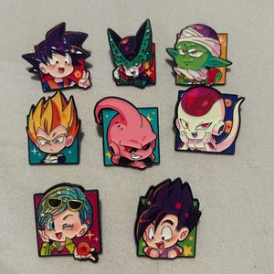 May include: A collection of eight enamel pins featuring chibi-style anime characters from Dragon Ball. The set includes Goku, Cell, Piccolo, Vegeta, Majin Buu, Frieza, Bulma, and Gohan, each set against a square background with star accents.