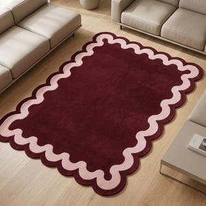 Hand tufted burgundy and pink scalloped area rug with a modern wavy border design, contemporary statement rug for living room or bedroom decor